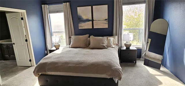a bedroom with a bed a flat tv screen and a large mirror next to a window