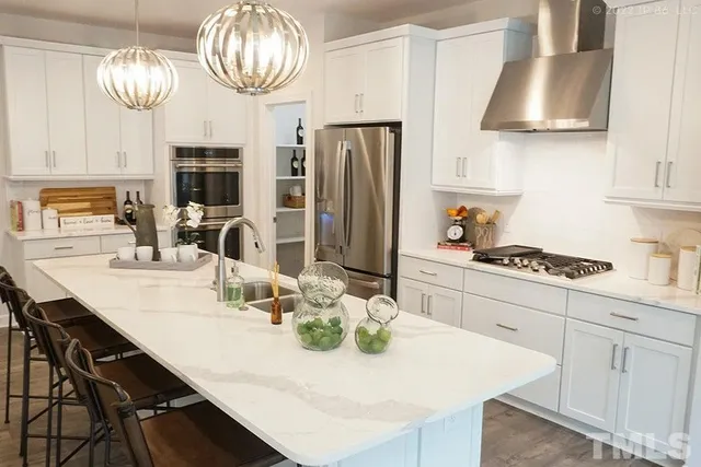 a kitchen with stainless steel appliances a table chairs and a refrigerator