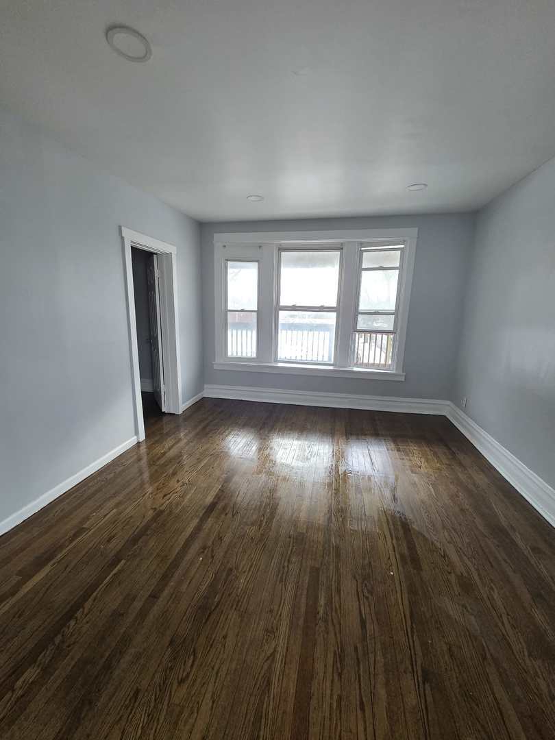 2704 East 77th Street, Unit 2 Chicago, IL 60649 - Photo 2 of 12 an empty room with wooden floor and windows