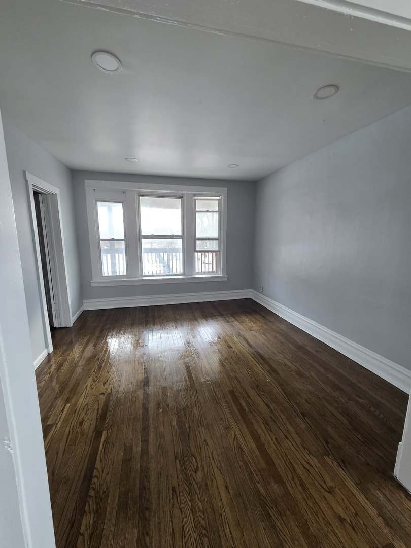 2704 East 77th Street, Unit 2 Chicago, IL 60649 - Photo 3 of 12 an empty room with wooden floor and windows