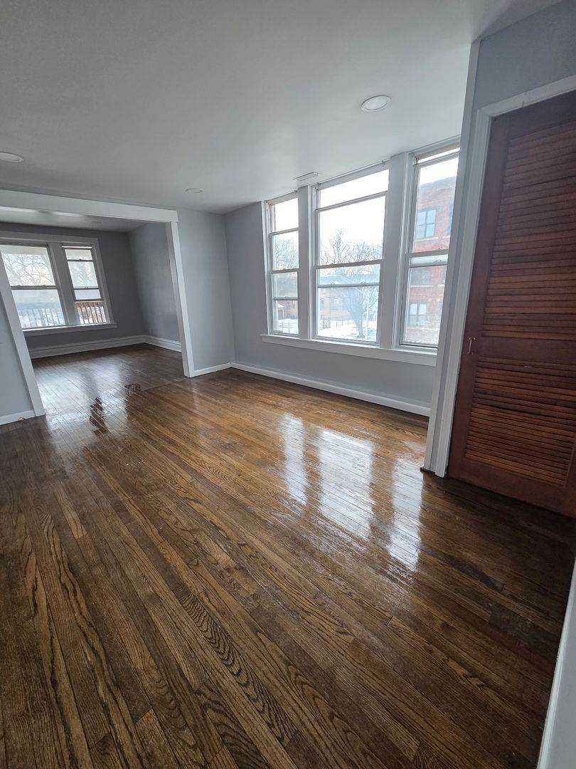2704 East 77th Street, Unit 2 Chicago, IL 60649 - Photo 5 of 12 wooden floor in an empty room with a window