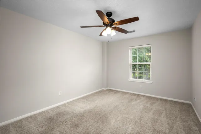 an empty room with a window and a fan