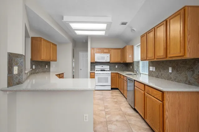 a large kitchen with stainless steel appliances granite countertop a stove a sink and a refrigerator