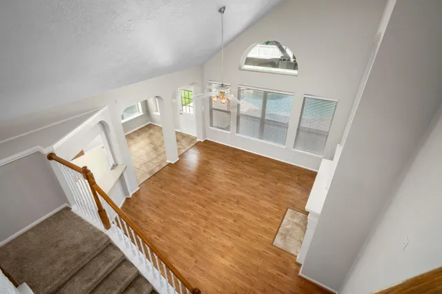 a view of an empty room with wooden floor and windows
