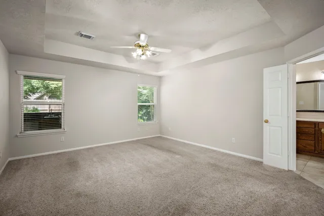 an empty room with windows and chandelier fan