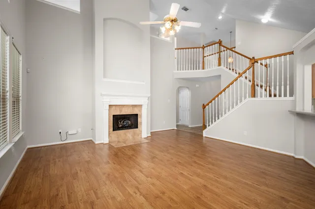 a view of an empty room with wooden floor and a fireplace