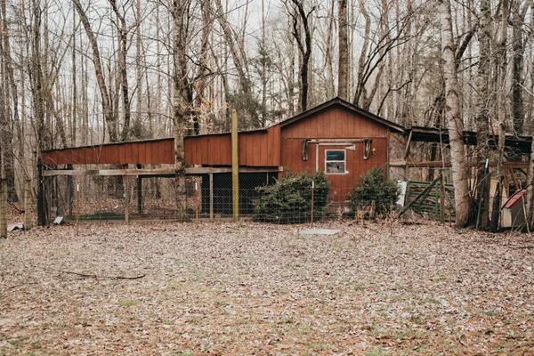 a house that has a tree in front of it with wooden fence