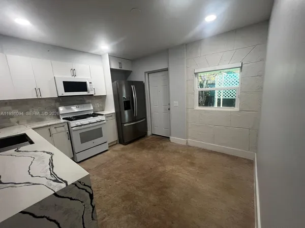 a kitchen with granite countertop a refrigerator and a stove top oven