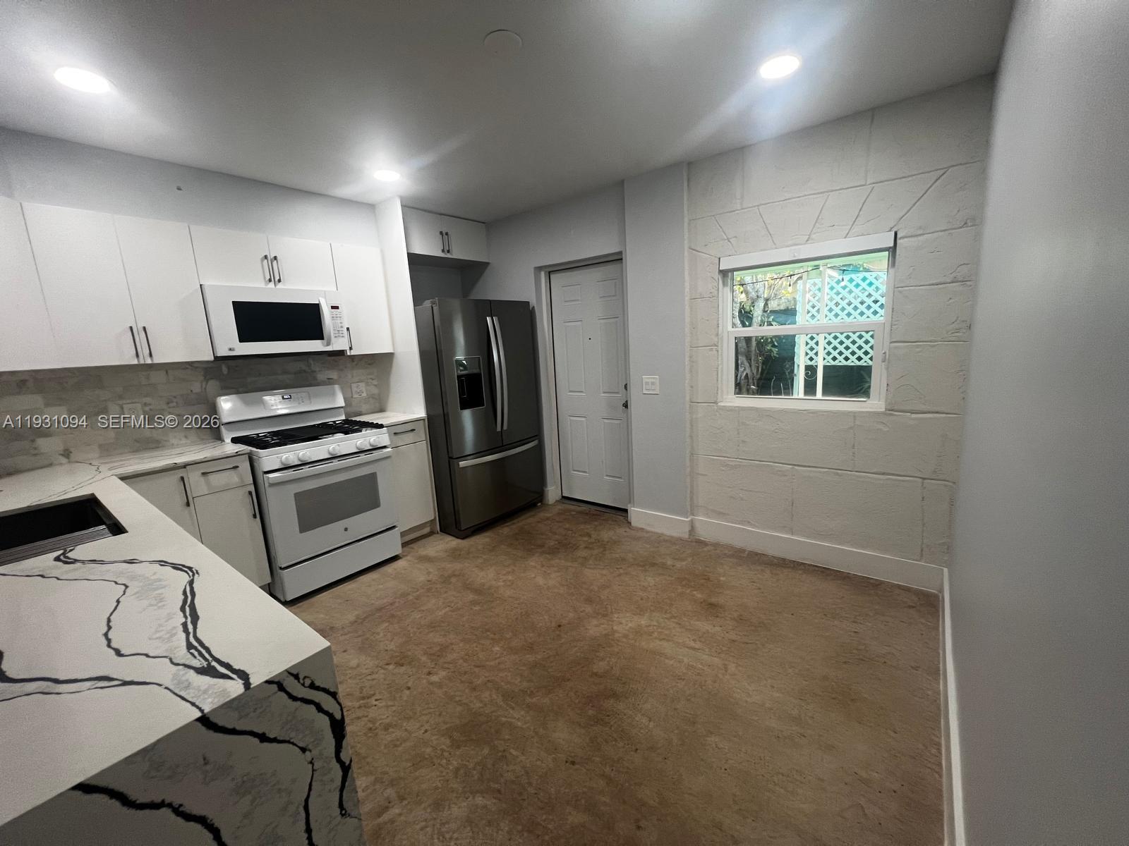 a kitchen with granite countertop a refrigerator and a stove top oven
