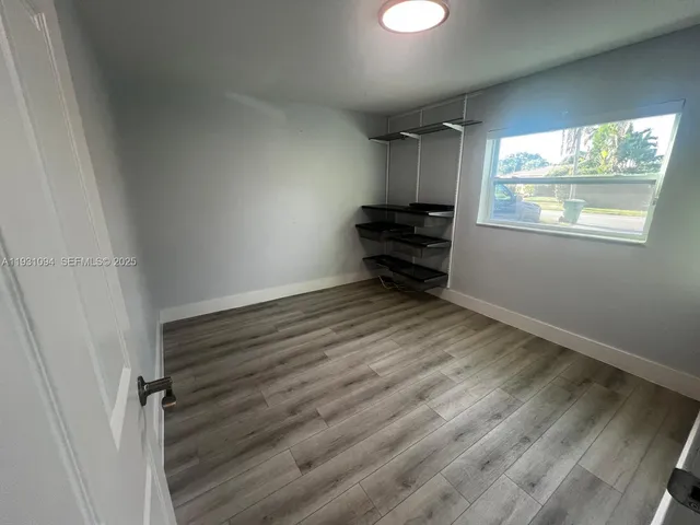 an empty room with wooden floor fan and windows