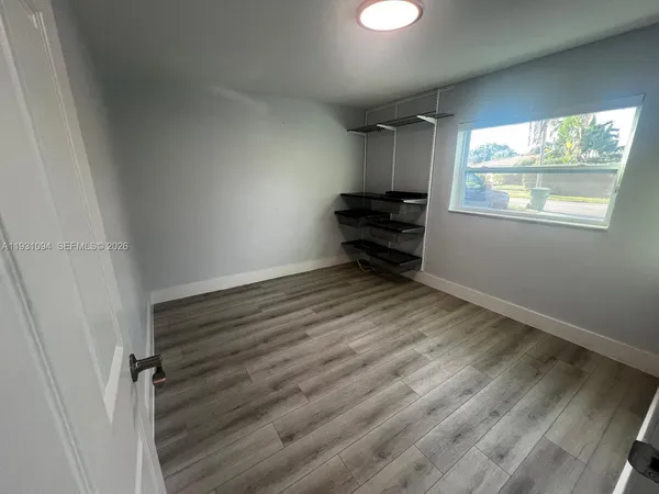 an empty room with wooden floor fan and windows