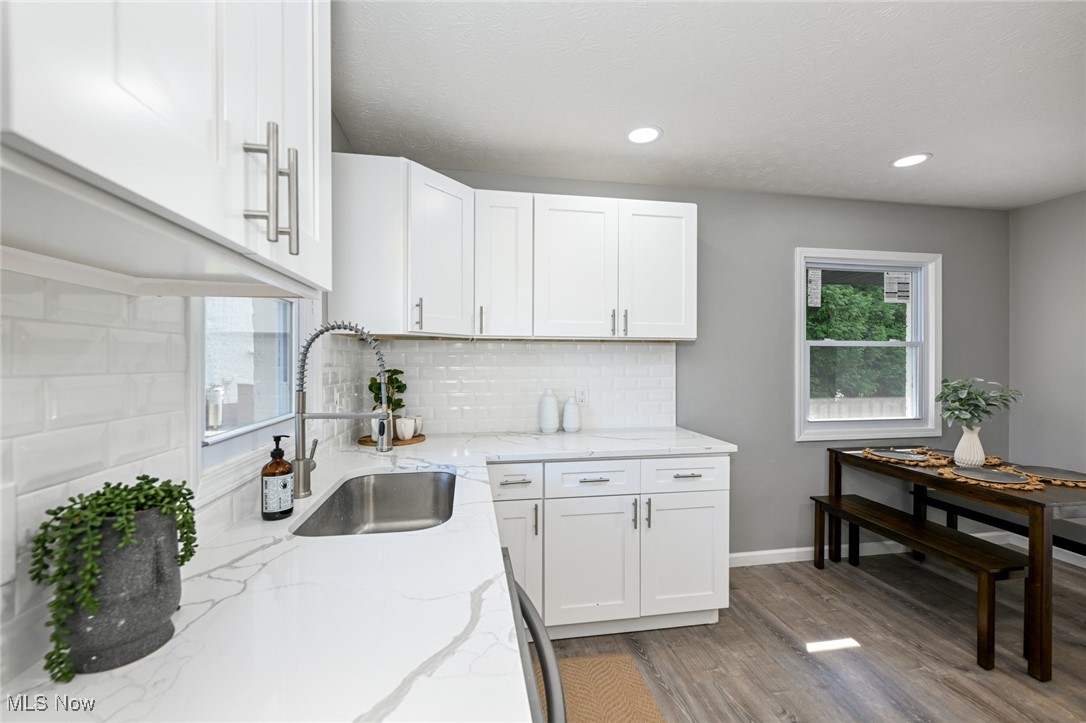 263 Forbes Road Bedford, OH 44146 - Photo 11 of 20 Kitchen featuring backsplash, white cabinetry, sink, and hardwood / wood-style floors
