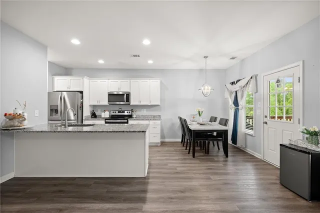 a kitchen with stainless steel appliances granite countertop a kitchen island hardwood floor sink stove dining table and chairs