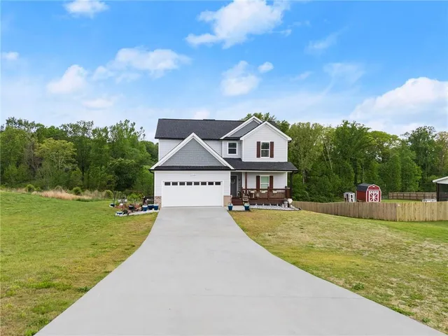 a view of a house with a big yard potted plants and large tree