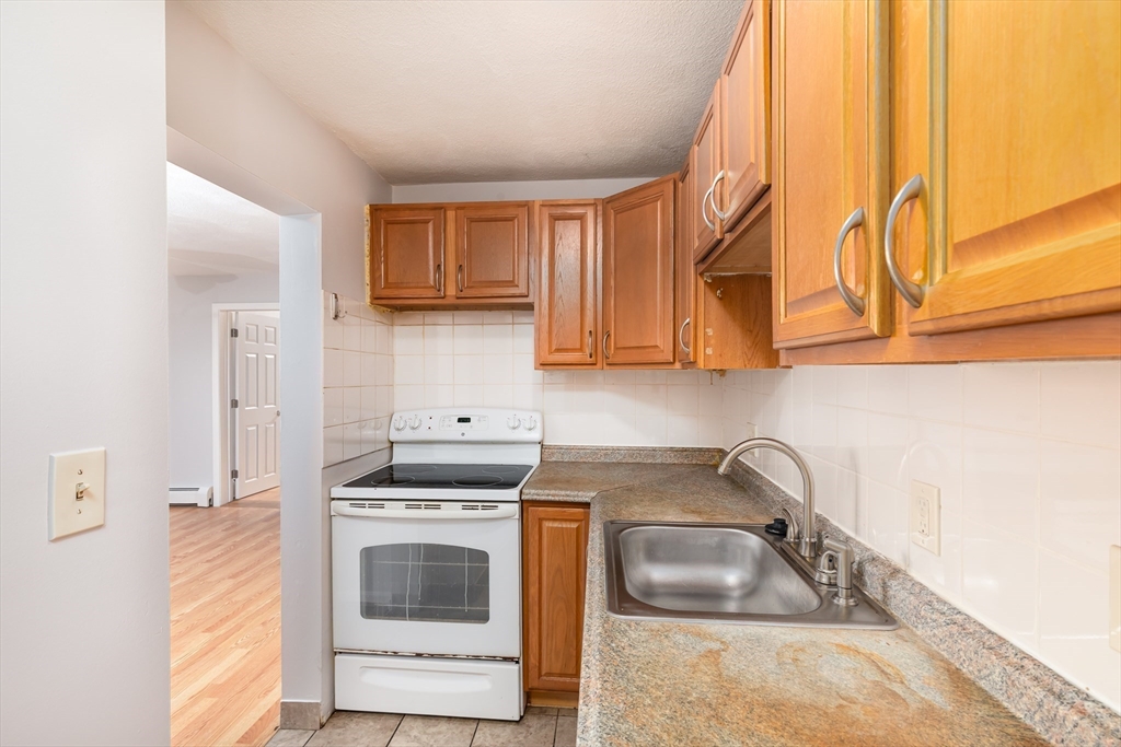 185 Lewis Street, Unit 4 Lynn, MA 01902 - Photo 11 of 20 a kitchen with granite countertop a sink a stove and cabinets