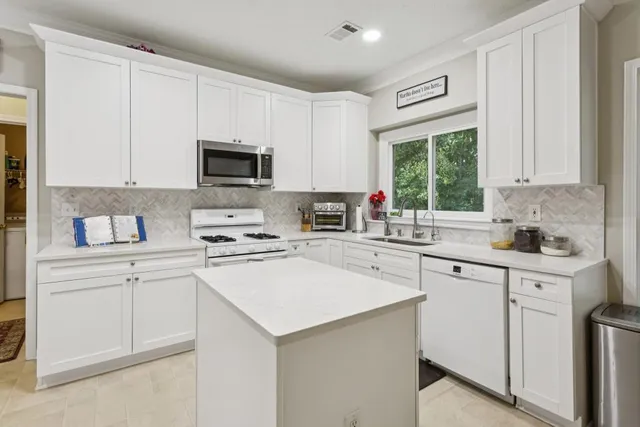 a kitchen with cabinets appliances a sink and a window