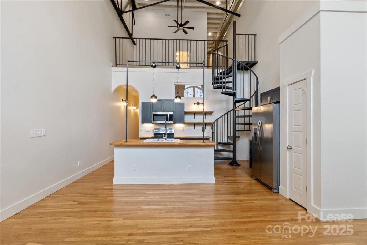 a view of kitchen island with stainless steel appliances granite countertop refrigerator and stove top oven