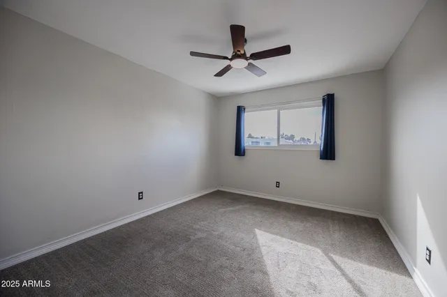 an empty room with closet and a ceiling fan
