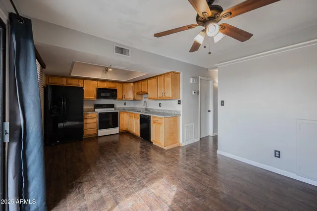 a kitchen with stainless steel appliances granite countertop a refrigerator a sink dishwasher a stove and white countertops with wooden floor