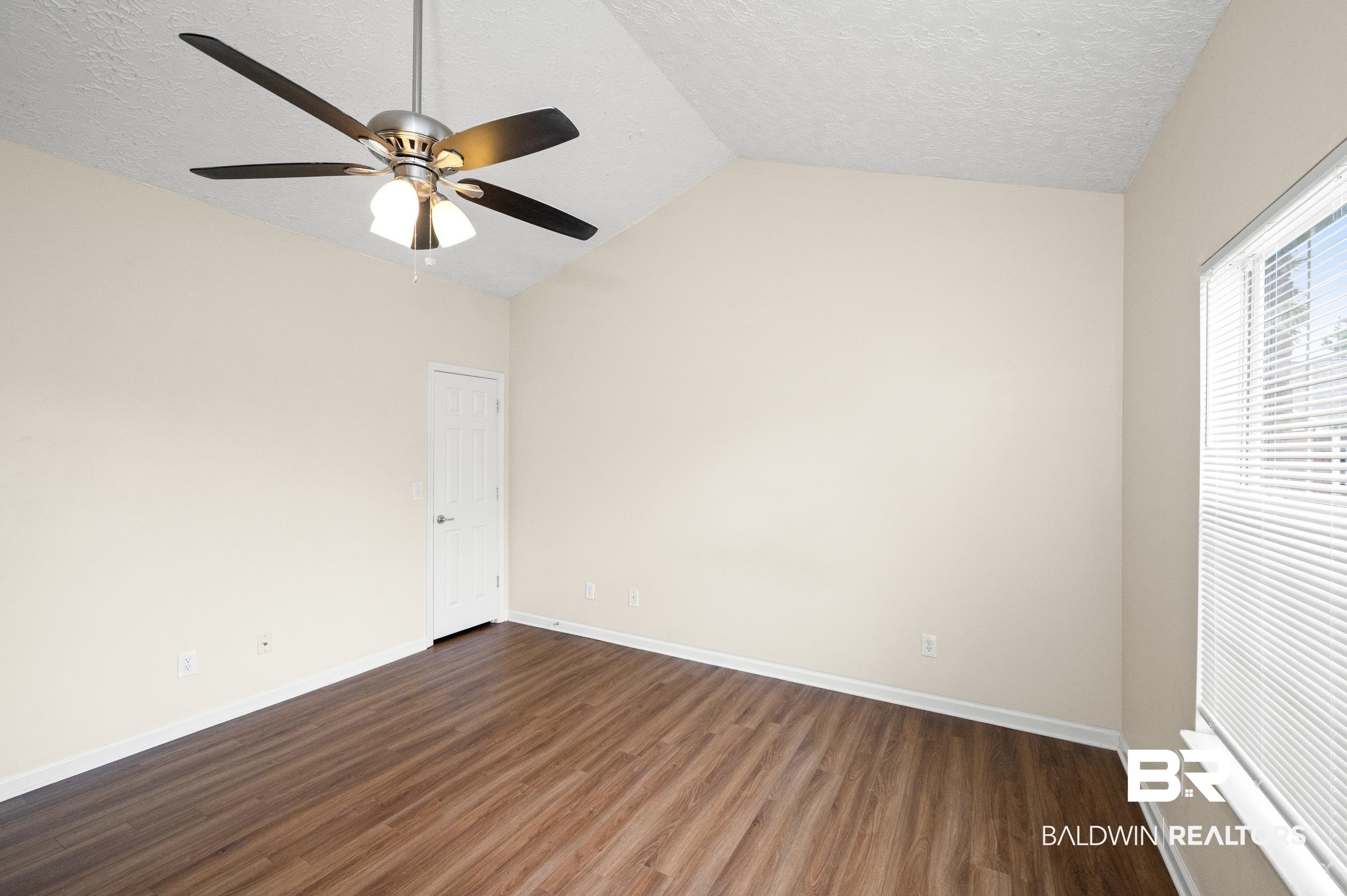 1333 Dominoe Trail Foley, AL 36535 - Photo 21 of 32 Empty room featuring a textured ceiling, ceiling fan, vaulted ceiling, and hardwood / wood-style flooring