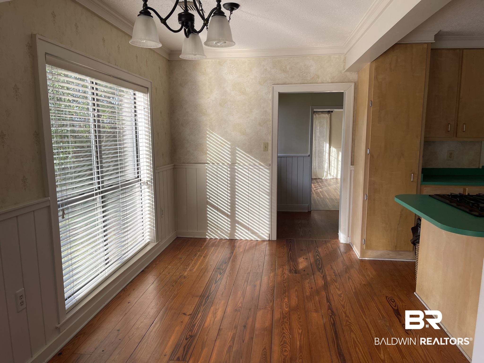 6621 Purvis Road Daphne, AL 36527 - Photo 18 of 59 Unfurnished dining area with a wainscoted wall, dark wood finished floors, crown molding, and suspended lighting