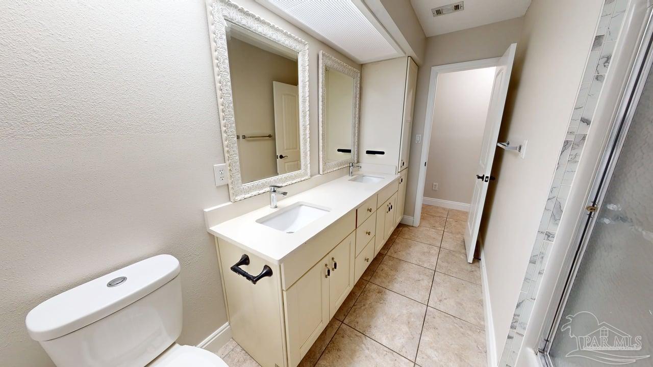 10111 Bristol Park Road Cantonment, FL 32533 - Photo 36 of 72 a bathroom with a double vanity sink toilet and mirror