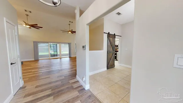 a view of a hallway with a chandelier fan and windows
