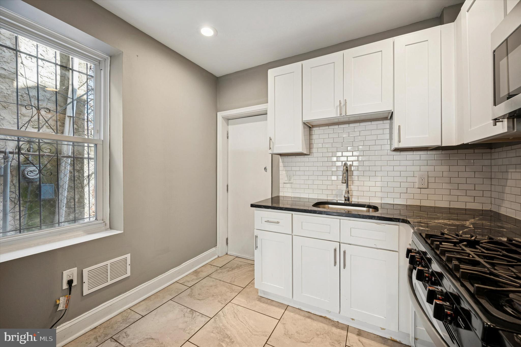 2147 North Marston Street Philadelphia, PA 19121 - Photo 5 of 15 a kitchen with granite countertop a stove a sink and white cabinets