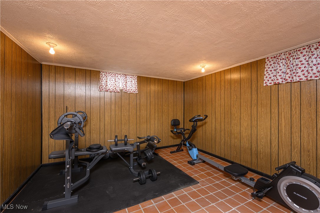 3015 Avalon Road Northwest Carrollton, OH 44615 - Photo 30 of 35 Exercise room featuring a textured ceiling, wooden walls, crown molding, and tile patterned flooring