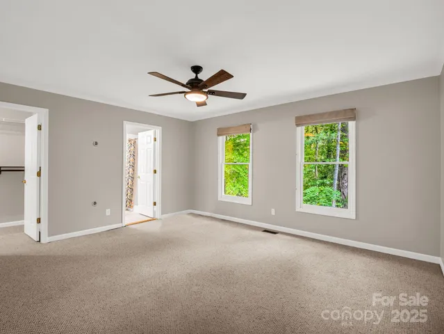 an empty room with windows and a ceiling fan