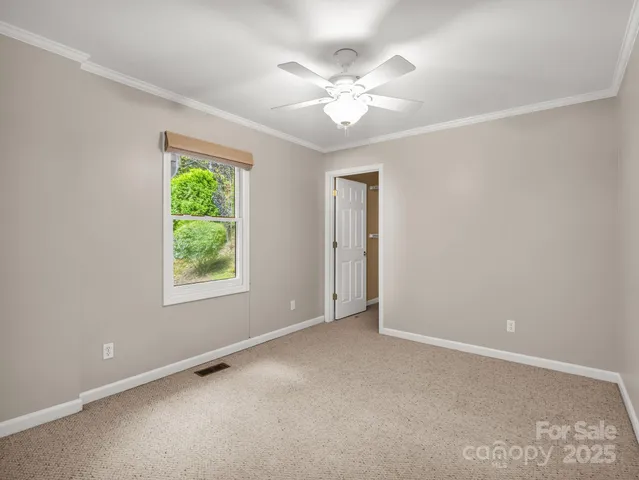 an empty room with a chandelier fan and windows