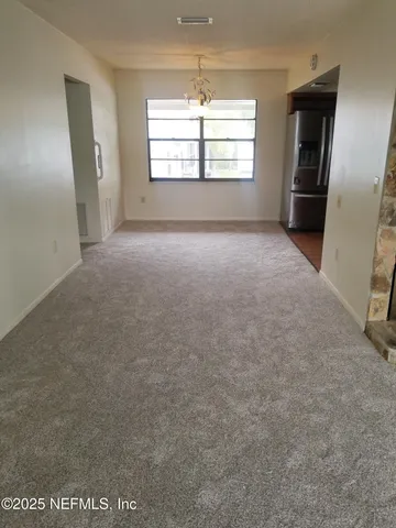 an empty room with windows and refrigerator