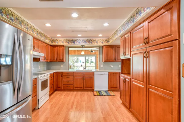 a kitchen with stainless steel appliances granite countertop a refrigerator a sink and wooden cabinets