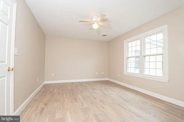 an empty room with wooden floor fan and windows