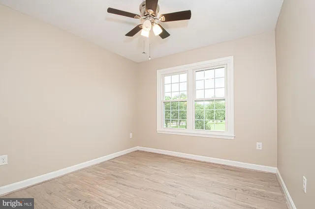 an empty room with wooden floor fan and windows