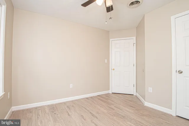 an empty room with a hardwood and ceiling fan