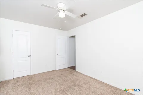 an empty room with windows and fan