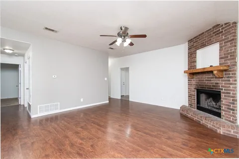 a view of empty room with wooden floor and a fireplace