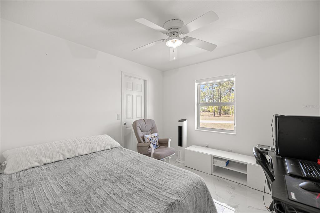 7191 Hemlock Road Ocala, FL 34472 - Photo 19 of 34 a bedroom with a bed and a chair