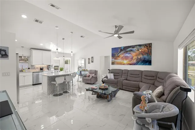 a living room with furniture kitchen view and a chandelier