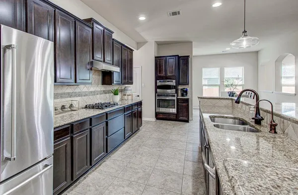 a kitchen with stainless steel appliances granite countertop a stove refrigerator and cabinets