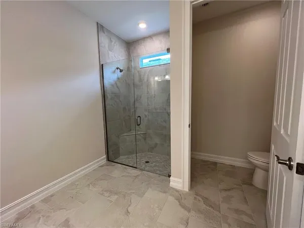 a bathroom with a granite countertop sink a toilet and shower