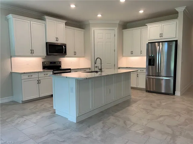 a kitchen with stainless steel appliances granite countertop a refrigerator sink and white cabinets