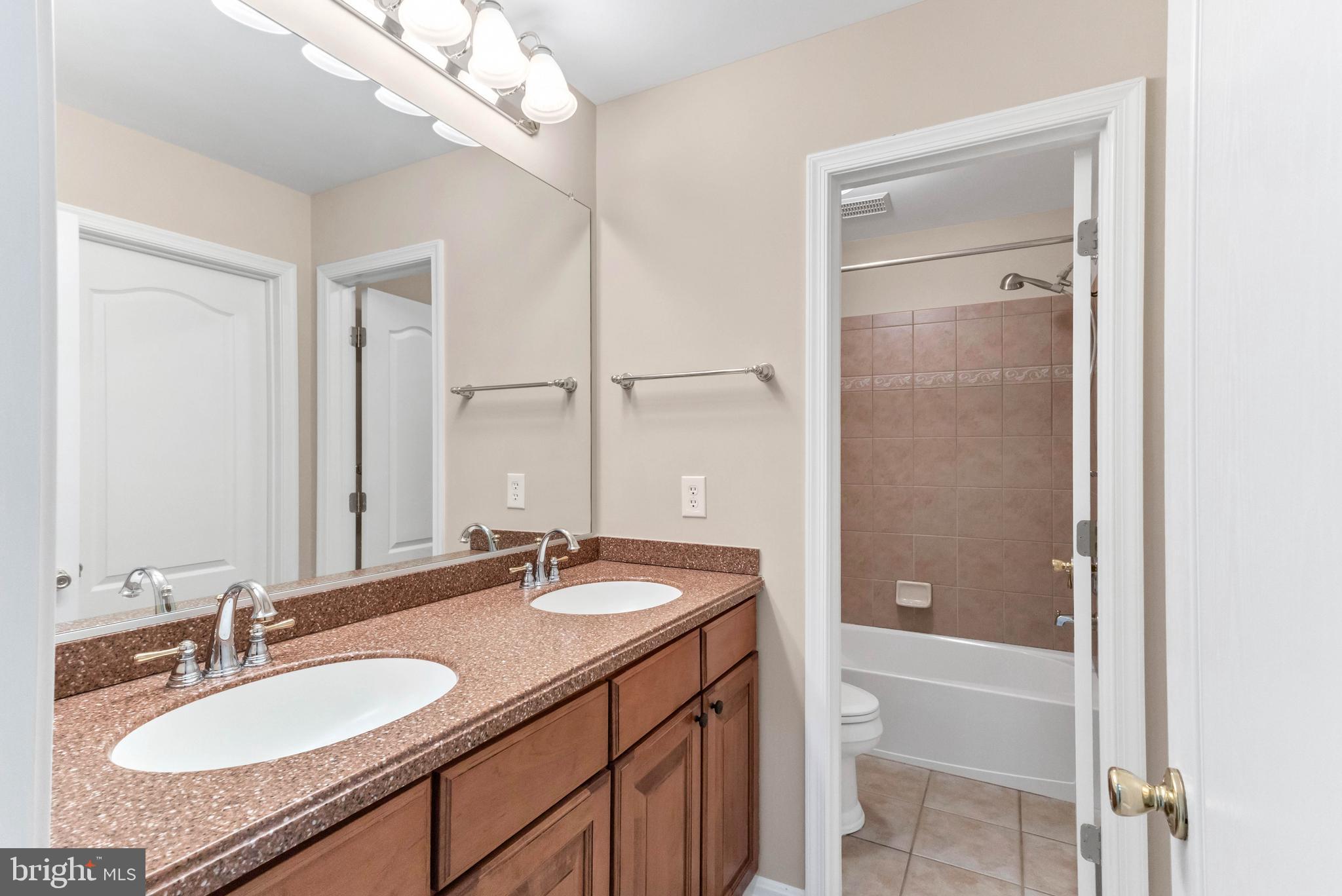 24872 Rivers Edge Road Millsboro, DE 19966 - Photo 49 of 80 a bathroom with a granite countertop sink a mirror and a bathtub