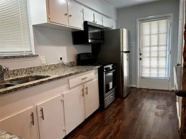 a kitchen with granite countertop a refrigerator sink and cabinets