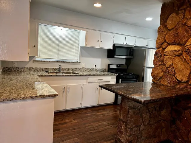 a kitchen with stainless steel appliances granite countertop a sink dishwasher a stove and a microwave oven with cabinets