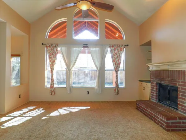 an empty room with windows and fireplace