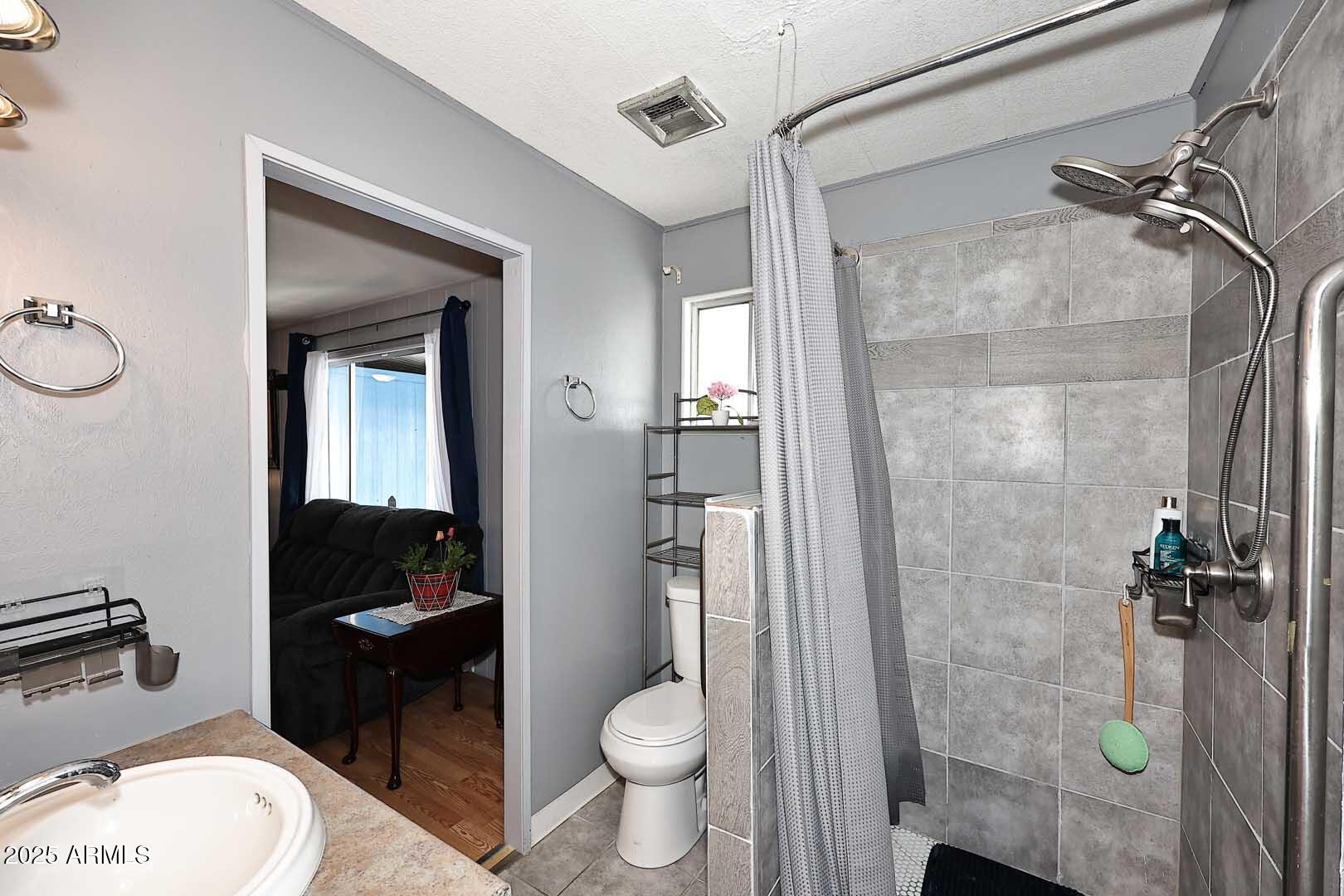 5201 West Camelback Road, Unit 243 Phoenix, AZ 85031 - Photo 19 of 27 a bathroom with a granite countertop toilet a sink and shower