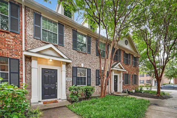 a view of a brick house with a large windows stairs and a large tree