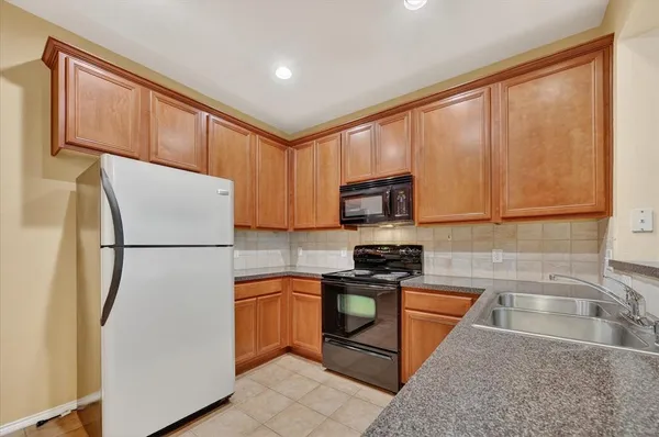 a kitchen with granite countertop wooden cabinets stainless steel appliances and a sink